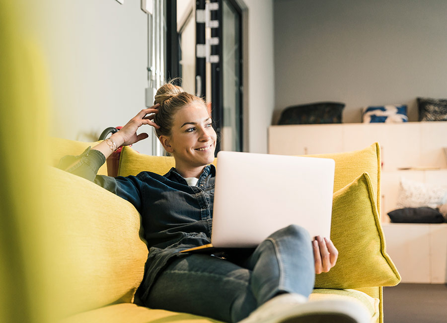 Woman using laptop on couch in office lounge. Pic: Getty Images