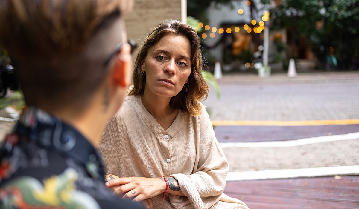 Same-sex couple sitting on the bench and having a serious conversation