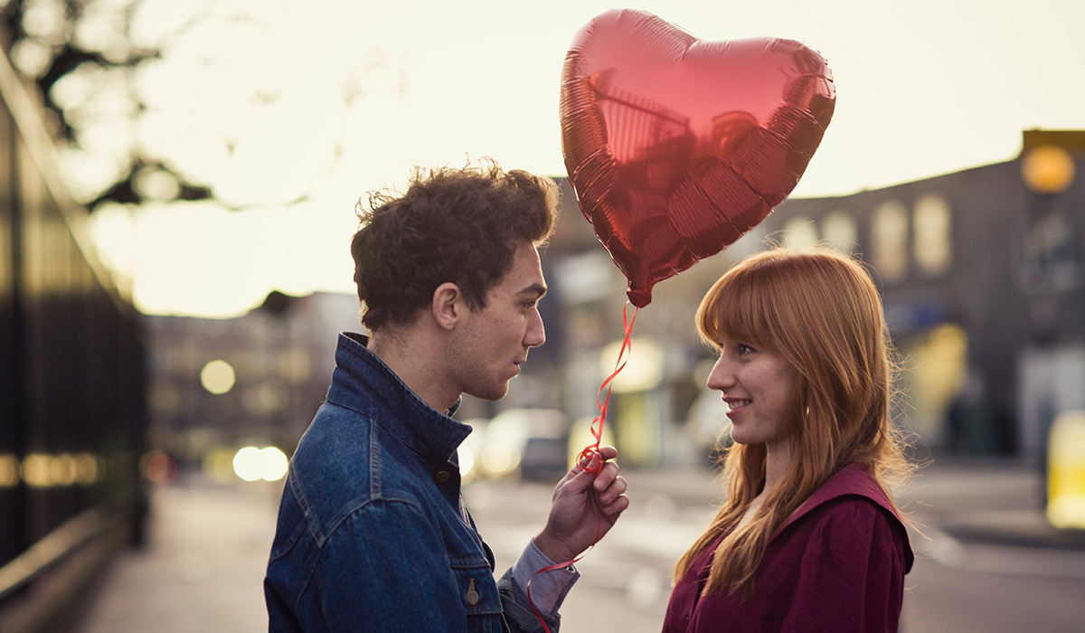 Couple walking with heart-shaped balloon