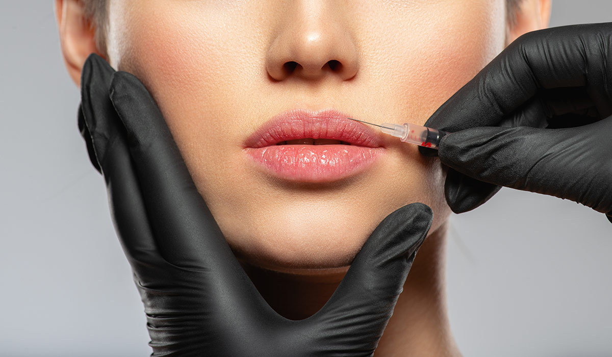 Young caucasian woman getting botox cosmetic injection in the lips. Beautiful woman gets botox injection in her face. Adult girl gets cosmetic injection of botox in a clinic. Beauty treatments